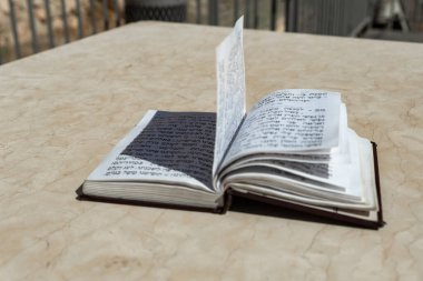The open holy book of Jews with the text of prayers in Hebrew - Tehelim, lies on a table near the Western Wall in the old city. of Jerusalem in Israel clipart