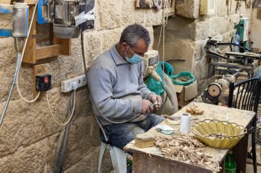 Beytüllahim, İsrail, 09 Aralık 2020: Bir işçi oturuyor ve İsrail 'in Beytüllahim kentindeki bir hediyelik eşya dükkanında zeytin ağacından hediyelik eşya yapıyor.