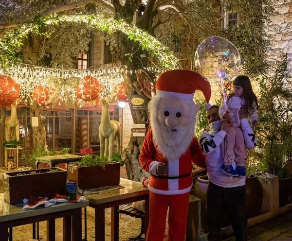 Hayfa, İsrail, 25 Aralık 2020: Turistler akşam saatlerinde İsrail 'in kuzeyindeki Hayfa' daki Alman Kolonisi 'nde Noel Baba ile fotoğraf çekiliyor.