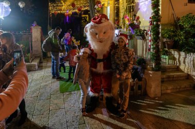 Hayfa, İsrail, 25 Aralık 2020: Çocuklar akşam saatlerinde İsrail 'in kuzeyindeki Hayfa' daki Alman Kolonisinde Noel Baba ile fotoğraf çekiliyor.