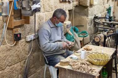 Beytüllahim, İsrail, 09 Aralık 2020: Bir işçi oturuyor ve İsrail 'in Beytüllahim kentindeki bir hediyelik eşya dükkanında zeytin ağacından hediyelik eşya yapıyor.