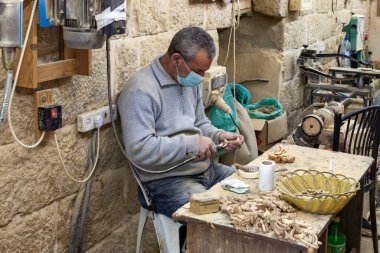 Beytüllahim, İsrail, 09 Aralık 2020: Bir işçi oturuyor ve İsrail 'in Beytüllahim kentindeki bir hediyelik eşya dükkanında zeytin ağacından hediyelik eşya yapıyor.