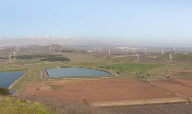 Yakındaki Benthal Dağı 'ndan panoramik bir manzara, yerleşim alanları, tarlalar, rüzgar türbinleri ve kuzey İsrail' deki Golan Tepeleri 'ndeki Hermon Dağı' nın karlı zirvesi.