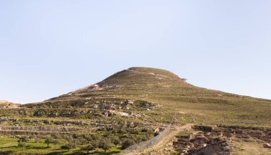 The filled artificial hill in which they are located the ruins of the palace of King Herod - Herodion,in the Judean Desert, in Israel clipart