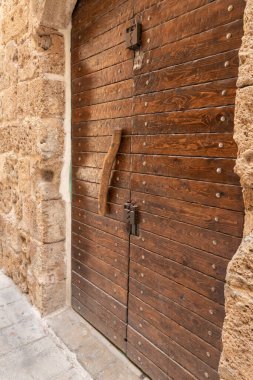 İsrail 'in kuzeyindeki Acre şehrinin limanındaki iskan avlusunun girişinde tahta saplı antik ahşap kapı.