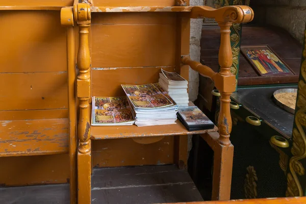 Religious brochures, books and videodiscs in Arabic lie on a wooden chair in the interior of the St. Jacobs orthodox  cathedral Jerusalem in Christian quarters in the old city of Jerusalem, Israel