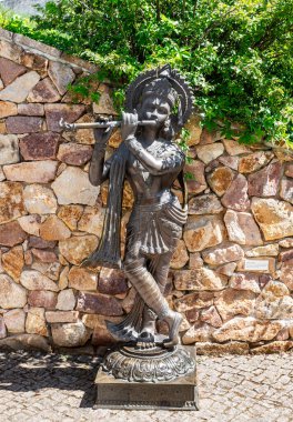 Prague, Czech Republic, May 15, 2024 : Bronze statue of the Indian god Krishna playing the flute on territory of the Prague Zoo in Czech Republic