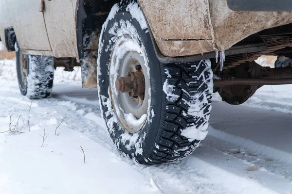 Studded winter car tires on an old car on snowy road — Stock Image Studded winter car tires on an old car on snowy road Stock Picture
