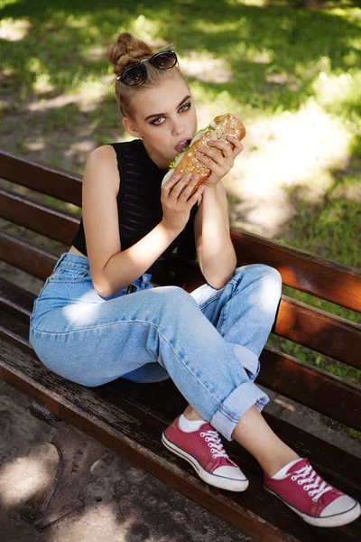Bokovky girt pózuje stravovací velký sendvič — Stock fotografie