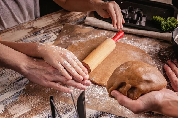 Mom and daughter hands hold a rolling pin. Molds and tools for baking homemade Christmas cookies. Rustic table top background. Homemade delicious traditional pastries