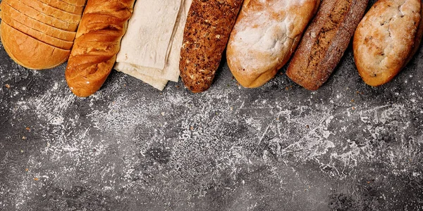 Food baking banner. Various types of fresh homemade bread on a gray concrete background. Top view. Horizontal shot. Copy space