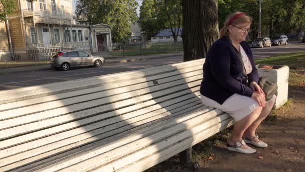 Ryssland, staden av Peterhof, 6 September 2015 vackra söta äldre kvinna sitter på en parkbänk blå — Stockvideo