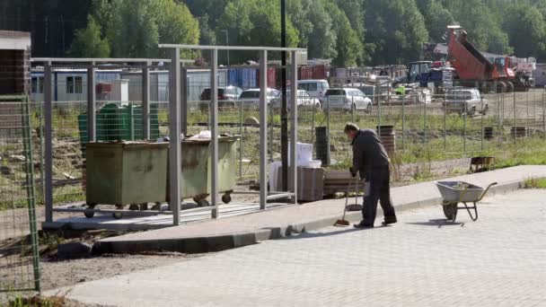 Oroszország, Szentpétervár, szeptember 11-én 2015-ig gondnok takarít ki rendetlenséget teremt az LEEH-ból származik az a parkoló terület autó söpri homok, járólap és járdára közelében — Stock videók