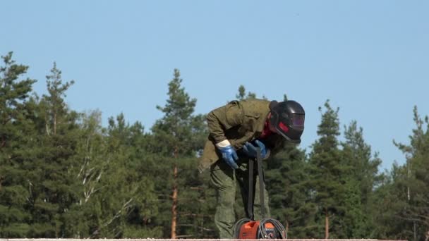 Russland, st. petersburg, 11. september 2015 schweißer nach der arbeit stapelschweißgerät hängt es an seiner schulter und entfernt vom arbeitsplatz — Stockvideo