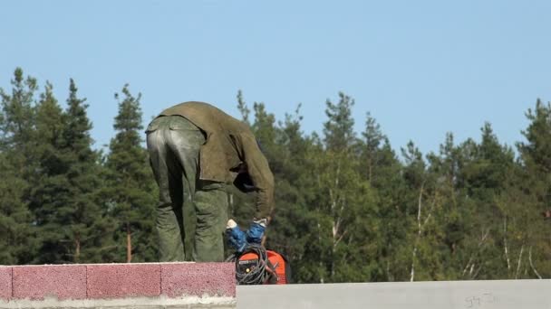 Rusia, pueblo de San Petersburgo uzigonty, 11 de septiembre de 2015 Soldador en una ropa de trabajo especial en el techo pliega la máquina de soldadura y la mueve a la otra parte para la aplicación de la soldadura — Vídeos de Stock