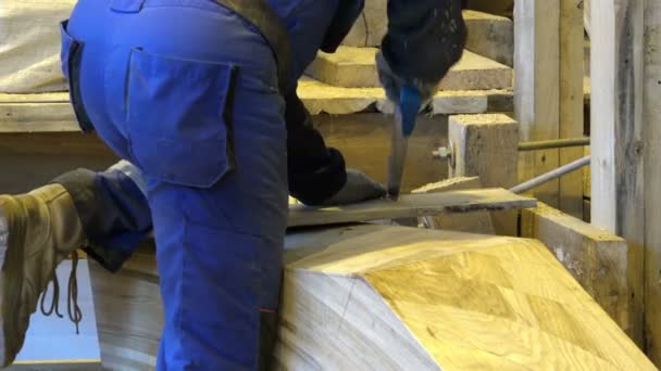 Trabajador en ropa y equipo especiales a expensas de una herramienta especial en forma de una sierra de mano aserrando una tabla de madera — Vídeos de Stock