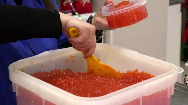 Der Verkäufer legt feinkörnigen Kaviar in den Behälter und sortiert ihn zum Wiegen — Stockvideo