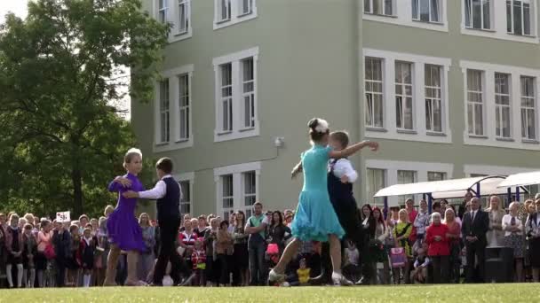 Desempenho de duas escolas de casais dançantes em uma grama verde na frente dos alunos no dia da festa do Conhecimento — Vídeo de Stock