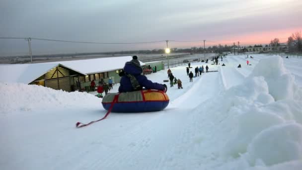 Περιφέρεια Λένινγκραντ Tuutari Park, 2 Ιανουαρίου 2016: χειμερινά πατινάζ ενήλικες και παιδιά σε Τσίζκεϊκ από τις χιονισμένες πλαγιές και απόκρημνους λόφους — Αρχείο Βίντεο