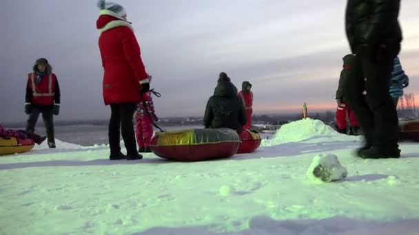 RUSIA, REGIÓN DE LENINGRAD PARQUE TUUTARI, 2 DE ENERO DE 2016: Padres y personal especializado rodaron sobre pasteles de queso niños con colinas nevadas para dar placer y alegría de un viaje — Vídeos de Stock