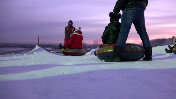 俄罗斯，列宁格勒地区图塔里公园，2016年1月2日：人们在雪地和冰坡上排队和乘坐管道 — 图库视频影像