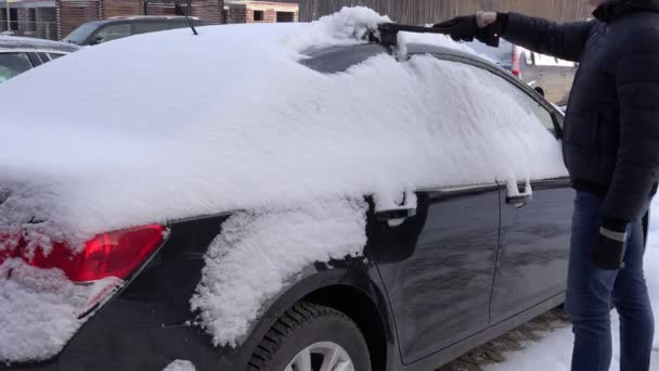 RUSSIA, Leningrado, Peterhof, 3 de janeiro de 2016: Escova de motorista limpa seu veículo na neve acumulada na camada corporal — Vídeo de Stock
