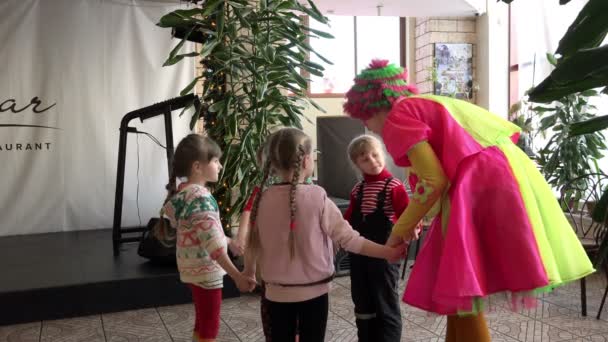 俄罗斯，圣彼得堡，2016 年 1 月 10 日︰ 在粉红色的黄色西装儿童小丑向孩子们解释游戏规则，并将其转换舞蹈 — 图库视频影像