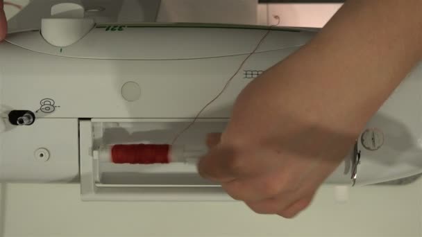 Krawcowa stawia szpuli czerwona nić na maszynę do szycia i nici rozciąga się na napinacz — Wideo stockowe
