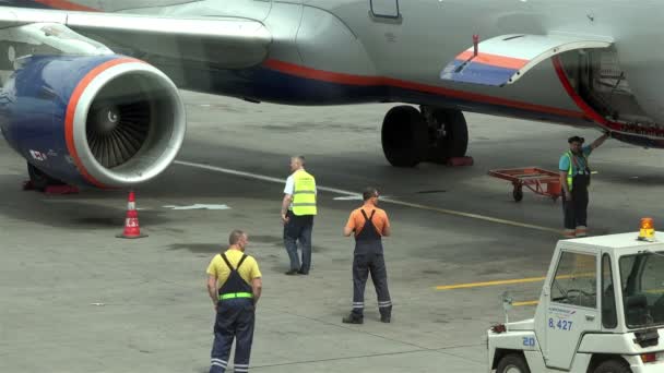 Aeroporto de Moscou Sheremetyevo, Rússia - 25 de junho de 2016: Trabalhador do aeroporto em macacões verdes fecha o compartimento de carga da aeronave depois de carregar contêineres de bagagem — Vídeo de Stock