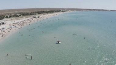 Turistler kıyı şeridi yakınlarında denizde yüzerler.