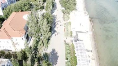 Güneşli bir günde, turistler sahil boyunca yürür.