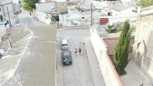 Um homem com duas filhas caminha por pequenas ruas — Vídeo de Stock