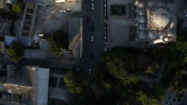 Kırmızı bir araba dar bir caddede yavaşça ilerliyor.