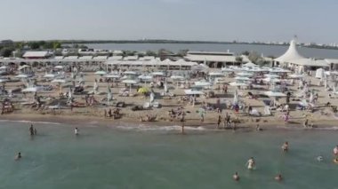 Kumsalda turistler için bir sürü şemsiye var.