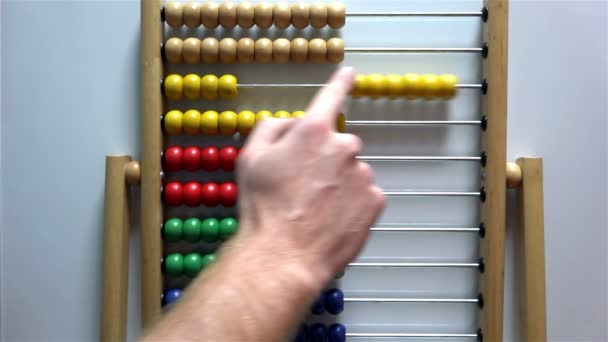 Man's hand moves the bones in the accounts of an abacus on white background — Stock Video