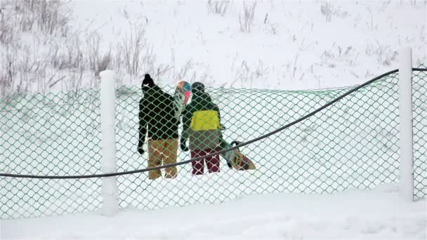 СЕНТ-ПЕТЕРСБУРГ, РОССИЯ - 27 декабря 2014 г. Два молодых спортсмена занимаются сноубордом с инвентарем в руках — стоковое видео