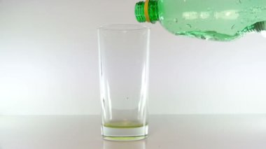 Yeşil plastik şişe su akışı dökülen ve sıvı bir bardak doldurur