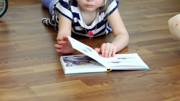 Rusia, San Petersburgo, 14 de marzo de 2015 - Niña acostada en el suelo y leyendo cuentos de hadas a través de las páginas del libro — Vídeo de stock