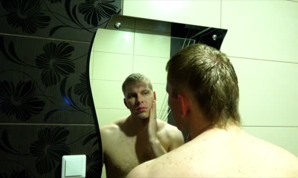 A young man checks the skin on the face to start shaving the hair — Stock Video