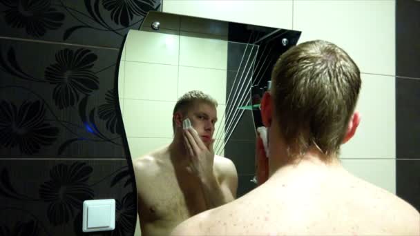 Ο άνθρωπος παίρνει κρέμα ξυρίσματος στο πρόσωπο με το δεξί του χέρι στο μπάνιο — Αρχείο Βίντεο