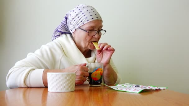 Russia, St. Petersburg, August 1, 2015 - Elderly woman sitting at a table drinking tea and looking Journal — Stock Video