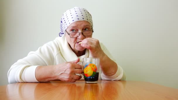 Gamla äldre sittande vid ett bord med glasögon och halsdukar och dricka te ensam — Stockvideo