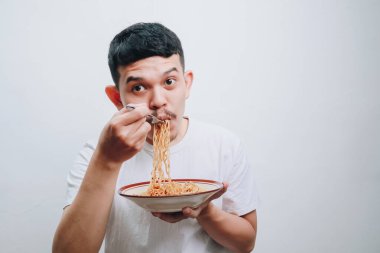 Genç bir adam bir kase erişteden zevk alır, neşe ve mutfak kültürünü ifade eder..