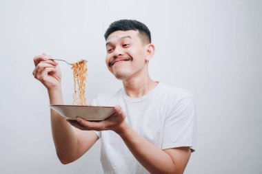 Neşeli bir adam, geniş bir gülümsemeyle lezzetli eriştelerin tadını çıkarıyor..