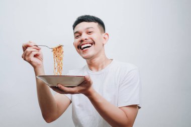 Neşeli bir insan bir tabak erişteden zevk alır, parlak bir şekilde gülümser..