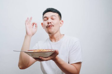 Neşeli bir adam lezzetli eriştelerin tadını çıkarıyor, saf tatmini ve zevki ifade ediyor..