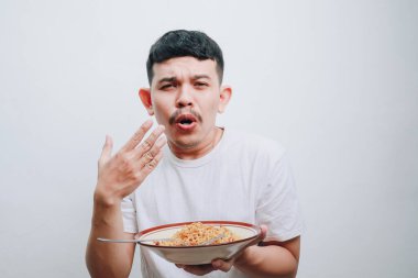 Bir adam bir kase eriştenin tadını çıkarırken şaşırmış bir yüz ifadesi sergiler..