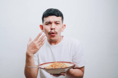 Bir adam basit bir arkaplanda bir kase eriştenin keyfini çıkarırken sevinç ifade eder..