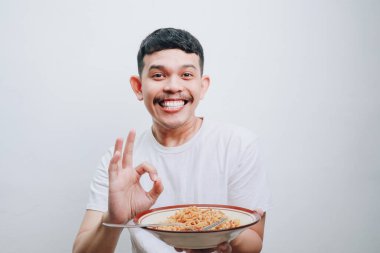 Mutlu genç bir adam, lezzetli erişteleri için heyecanlı bir şekilde baş parmağını kaldırır..