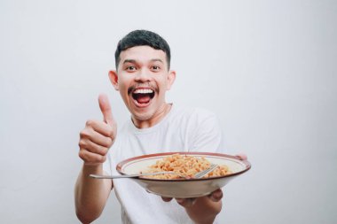 Neşeli genç bir adam gururla gülümseyerek bir kase erişteyle hava atar..